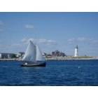 Scituate: A summer sailor passes historic Sciuate Light on his way out of the harbor and into open ocean water.